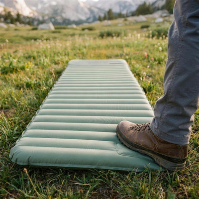 Hiking boot pressing the built-in foot pump at the foot end of a green Mattress Pro V2