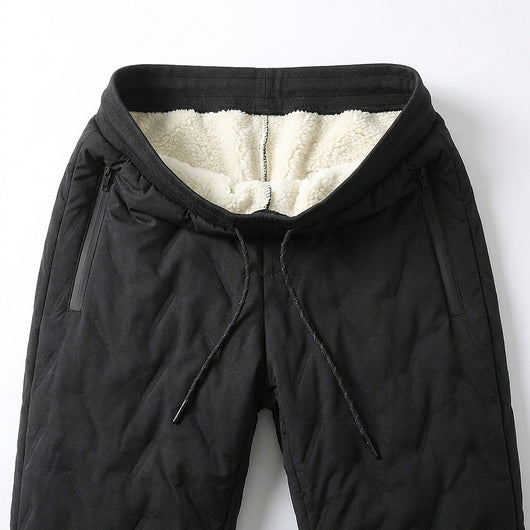 Waistband of the black winter pants folded open: cream sherpa fleece lining, drawcord and two zippered side pockets