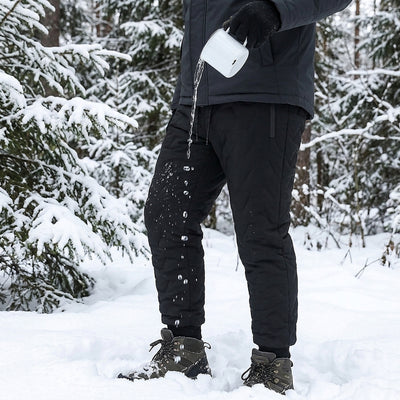 Water poured from a mug beading up and running off the black shell of the winter pants in a snowy forest