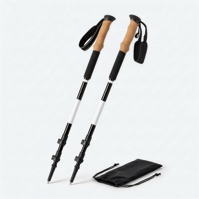 Pair of collapsible trekking poles with cork grips, black shafts with a white band, next to the black carry bag