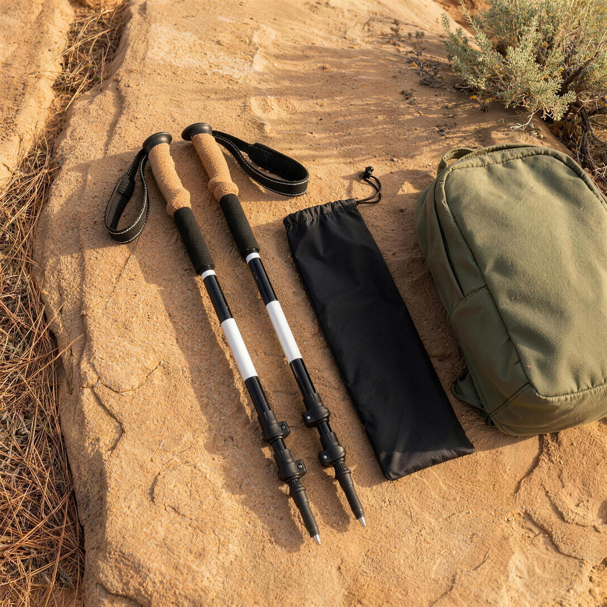 Two collapsed trekking poles on a sandstone slab beside their carry bag and a daypack